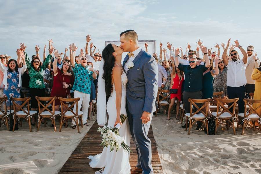 Beach wedding ceremony first kiss with celebrating guests — Ana Badillo Photography